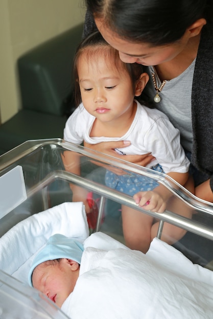 Foto mujer y niño niña mirando bebé recién nacido