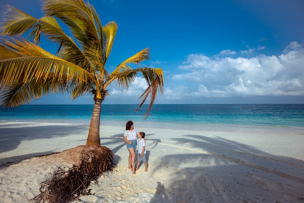 Mujer y niño de pie debajo de una palmera en el océano