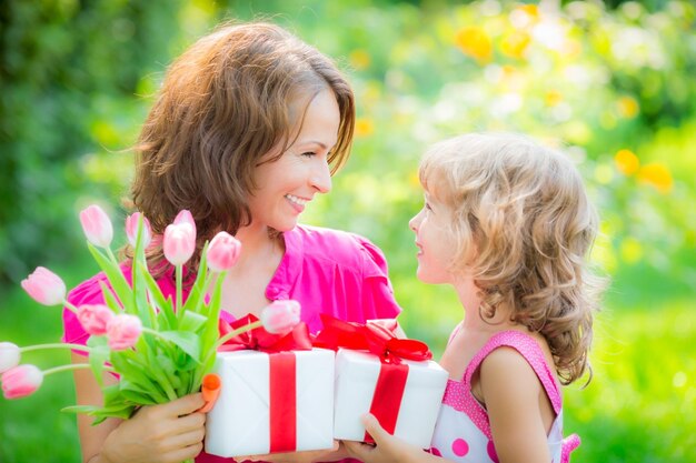 Mujer y niño con ramo de flores contra el fondo verde borroso Concepto de vacaciones familiares de primavera Día de la mujer