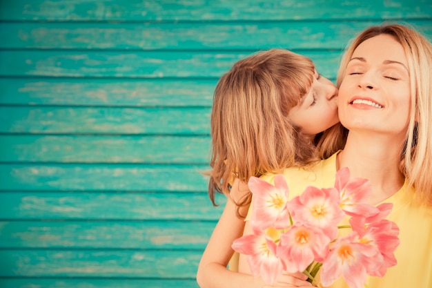 Mujer y niño con ramo de flores contra el fondo verde concepto de vacaciones familiares el día de la madre