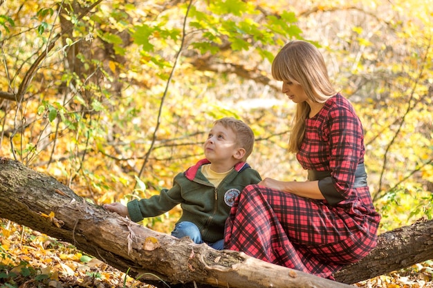 Una mujer y un niño se sientan en un tronco en el bosque.