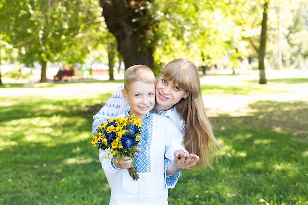 Una mujer y un niño sostienen flores y sonríen.