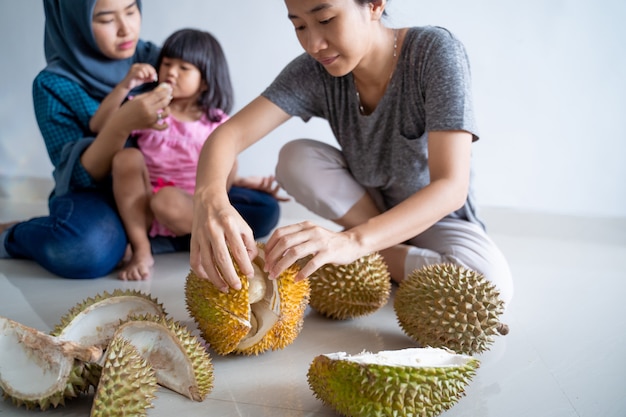 Mujer con niños comiendo fruta durian