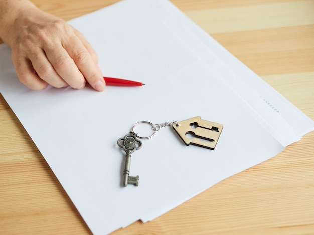 La mujer no se atreve a firmar documentos para comprar o alquilar un apartamento. La llave de la casa está sobre la mesa.