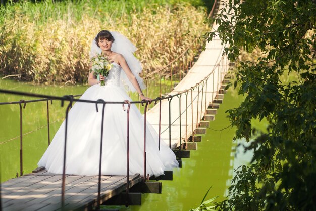 Mujer novia de pie en el puente sobre el río