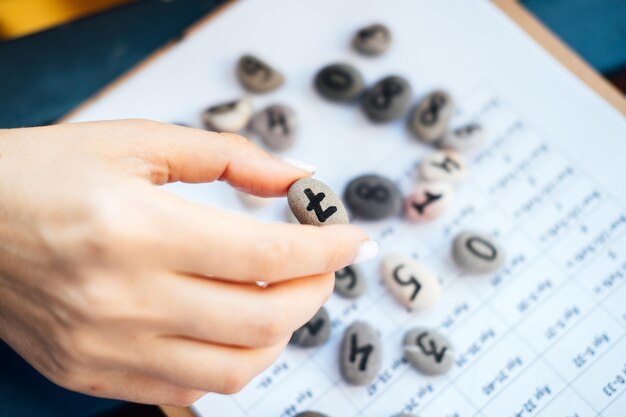 Mujer numeróloga mano con piedra de canto rodado con el número siete 7 Concepto de números de numerología Numerología Calcular el camino de la vida y los números del destino Enfoque selectivo