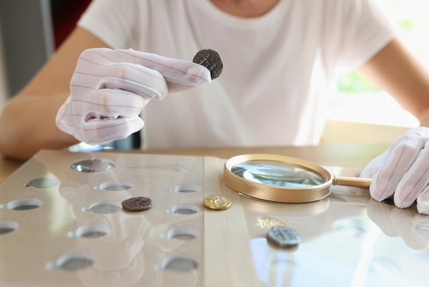 Mujer numismática examinando moneda con lupa