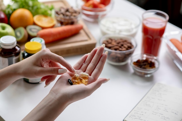 Mujer nutricionista profesional revisando suplementos dietéticos en la mano rodeada de una variedad de frutas, nueces, verduras y suplementos dietéticos en la mesa