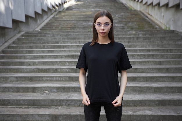 Mujer o niña con camiseta negra de algodón en blanco con espacio para su logotipo, maqueta o diseño en estilo urbano informal