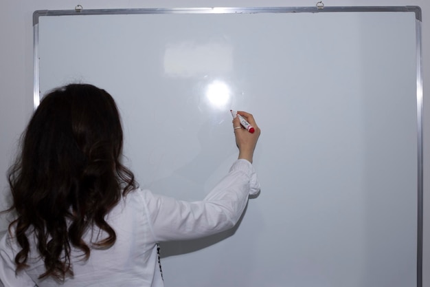 Mujer o profesora con marcador escribiendo a bordo.