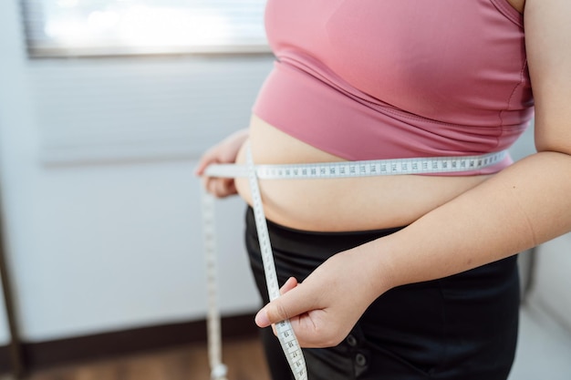 Foto mujer obesa con barriga gorda en concepto de dieta mujer con sobrepeso tocando su barriga gorda y quiere perder peso mujer gorda su cintura con un centímetroxa forma saludable