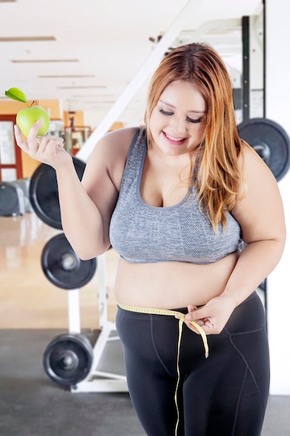 Mujer obesa con cinta métrica y manzana