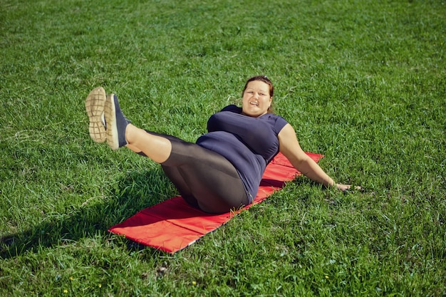 Mujer obesa hace levantamientos de piernas para adelgazar y cuerpo en forma