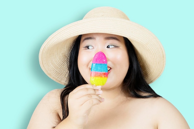 Mujer obesa sosteniendo un helado con ojos entrecerrados