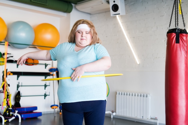 Mujer obesa trabajando con hula hoop