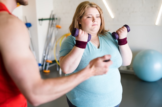 Mujer obesa trabajando con pesas