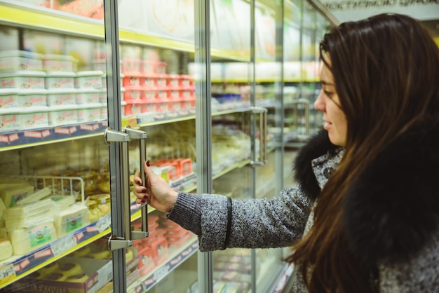 Mujer obtener queso de la nevera en el supermercado