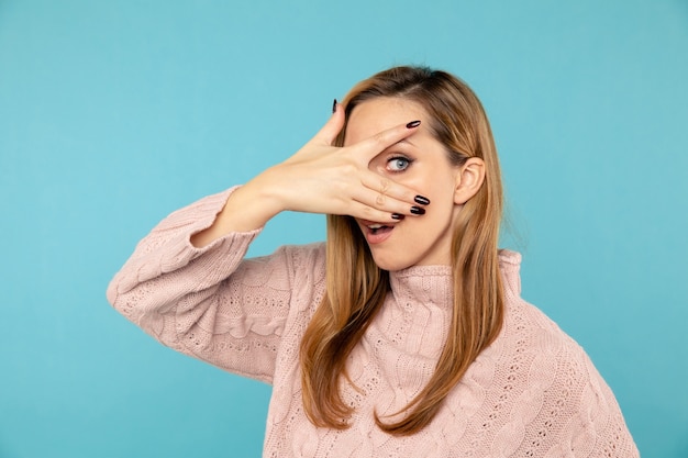 Foto mujer ocultando su rostro y mirando a través de sus dedos.