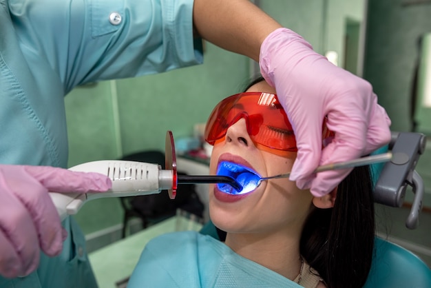 Foto mujer en odontología haciendo procedimiento de blanqueamiento con estomatólogo