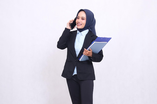 Una mujer de oficina asiática exclusiva con un hijab se para de lado alegremente llamando a la gente y llevando