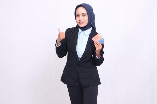 mujer de oficina asiática madura en hijab de pie feliz gestando pulgares hacia arriba bien bueno y trayendo débito c