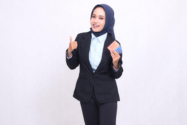 mujer de oficina asiática madura en hijab de pie feliz gesto pulgares hacia arriba como agradable y llevar crédito débito