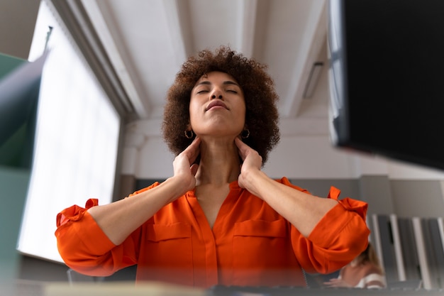 Foto mujer en la oficina estirándose durante un día de trabajo