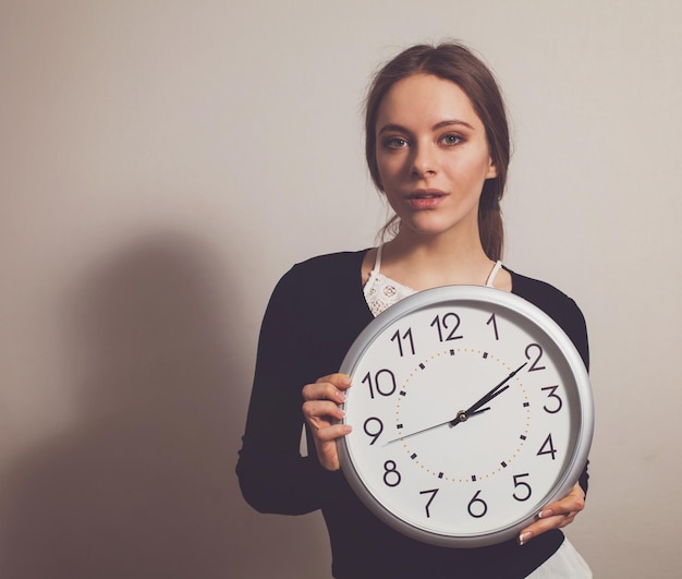 Foto mujer, en, oficina, con, grande, reloj blanco