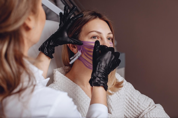 La mujer en la oficina de salones de belleza recibe un procedimiento de grabación para tensar la piel de su cara