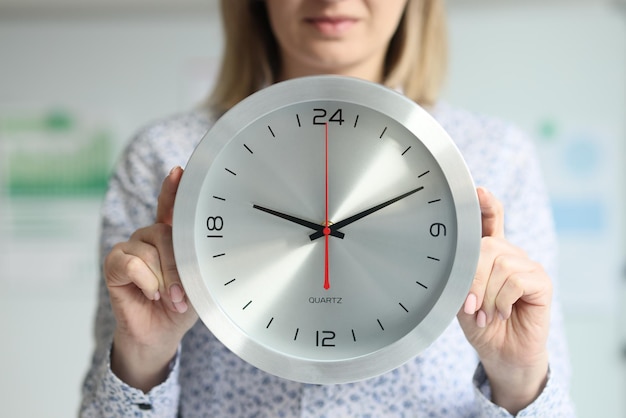 Foto una mujer en la oficina sostiene un elegante reloj de pared una empresaria de plazo de trabajo de horas extras de primer plano