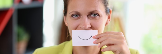 La mujer en la oficina sostiene el papel con una sonrisa feliz frente a su boca éxito de negocios y feliz