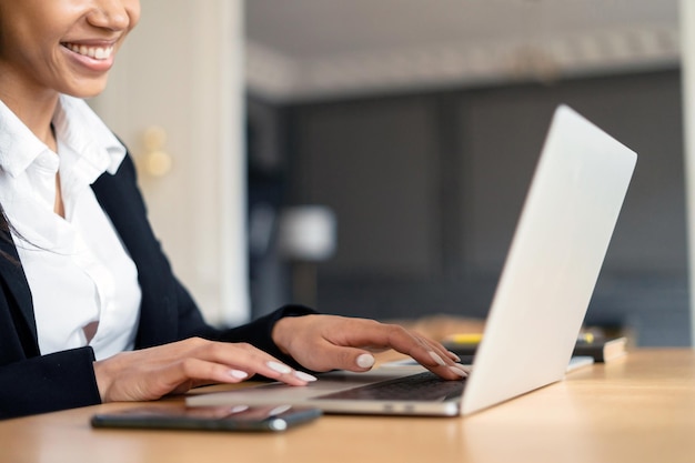 Foto una mujer en una oficina con traje de negocios usa una computadora portátil que funciona en línea