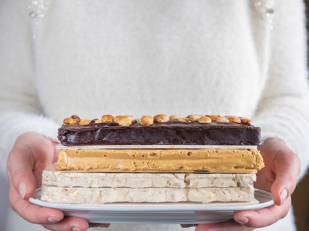 Mujer ofrece bandeja de turrón de chocolate y almendras. Comida típica española.