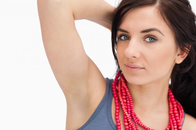 Foto mujer de ojos azules posando con un collar de cuentas rojas