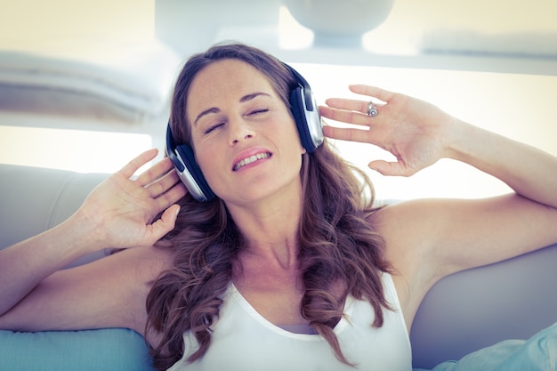 Mujer con los ojos cerrados escuchando música en el sofá