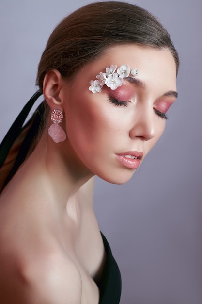 Mujer de ojos de maquillaje de primavera con flores blancas. Maquillaje de ojos de belleza floral creativa. Cosmética de pestañas con flores de verano.