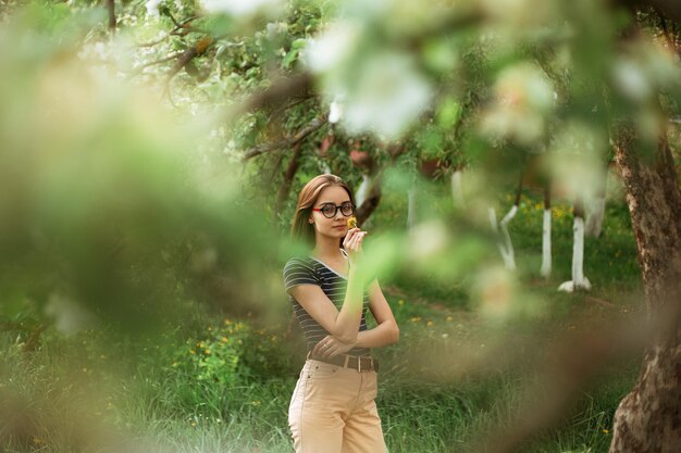 mujer oliendo flor aromática de diente de león mientras está de pie en un jardín natural