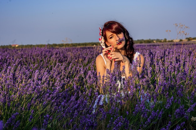 Mujer oliendo una flor en un campo de flores de lavanda