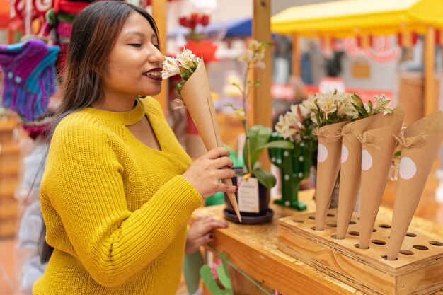 Mujer oliendo flores en un puesto en el mercado