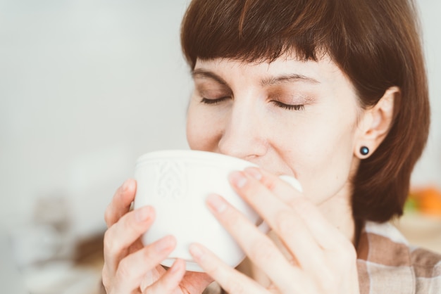 Mujer oliendo el olor a café de la taza.