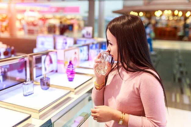 Foto mujer oliendo perfume mientras está de pie en la tienda