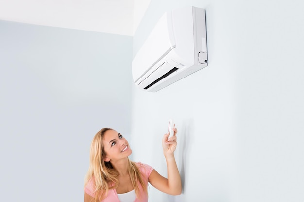 Mujer operando el aire acondicionado con un control remoto