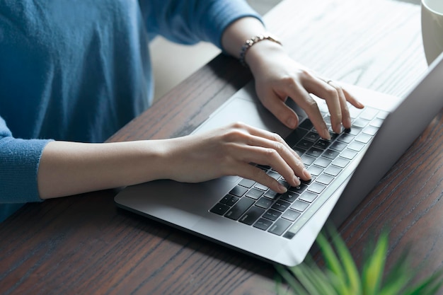 Mujer operando una computadora portátil sobre la mesa en la habitación