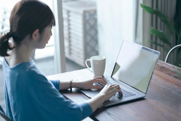 Mujer operando una computadora portátil sobre la mesa en la habitación