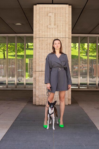 Mujer optimista en traje gris sonriendo y jugando con perro