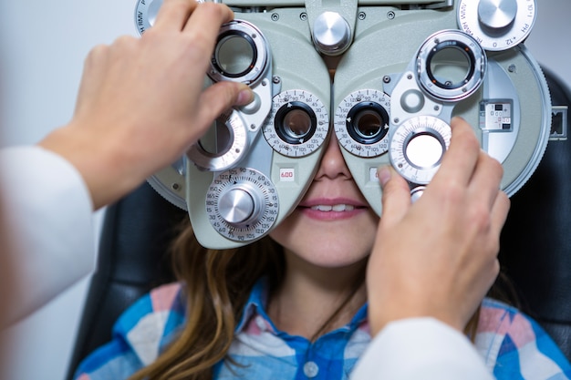 Mujer optometrista examinando paciente joven en foróptero