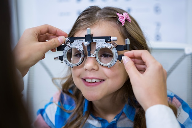 Mujer optometrista examinando paciente joven con marco de prueba