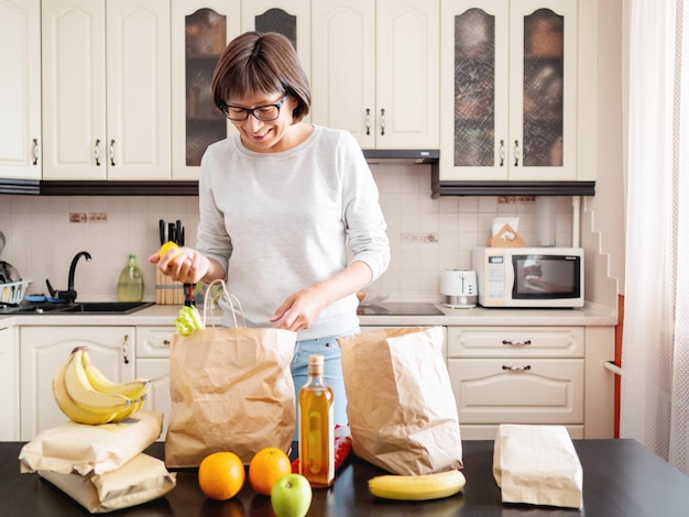 La mujer ordena las compras en la cocina servicio de suscripción de entrega de comestibles de la tienda de comestiables