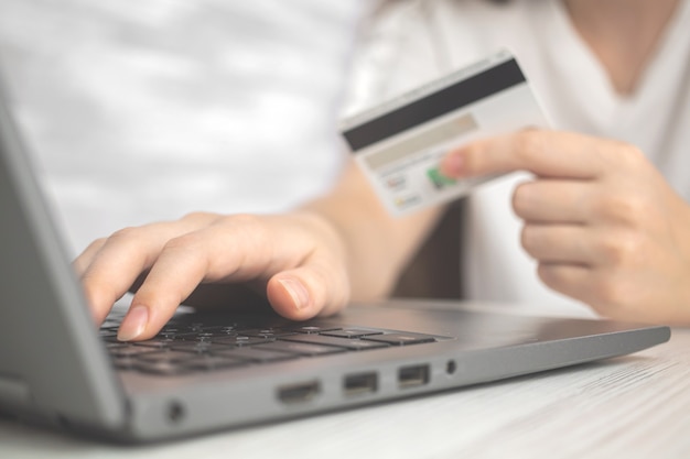 Mujer con ordenador portátil con tarjeta de crédito en mano. Concepto de compras en línea, gastar dinero y comercio electrónico. Foto de fondo de banca por Internet