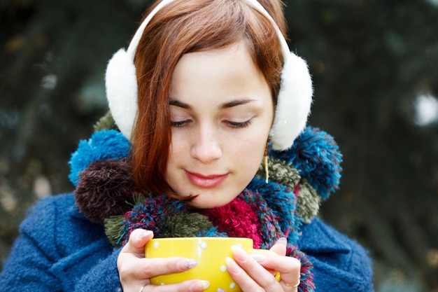 Mujer de otoño bebiendo café Concepto de otoño de mujer joven disfrutando de una bebida caliente de una taza de café desechable en el paisaje de otoño Serena feliz raza mixta Modelo femenino asiático caucásico en el parque forestal de la ciudad